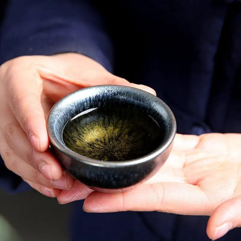 Dark ceramic teacup with tea from Glacier Tea Set featuring crystalline and Tenmoku glaze