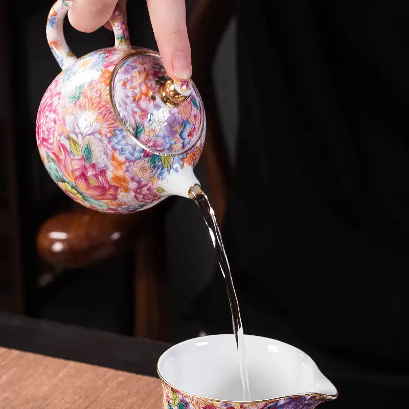 Gold floral enamel teapot pouring liquid showcasing Jingdezhen enamel art and floral design