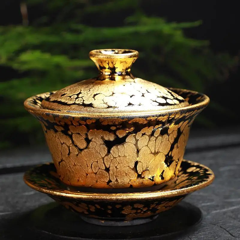 Gold-patterned black tea set featuring a fairness pitcher and gold Jian Zhan tea accessories