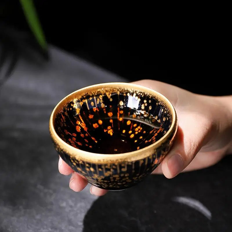 Dark ceramic teacup with gold accents from Golden Drops, ideal for Jian Zhan tea connoisseurs