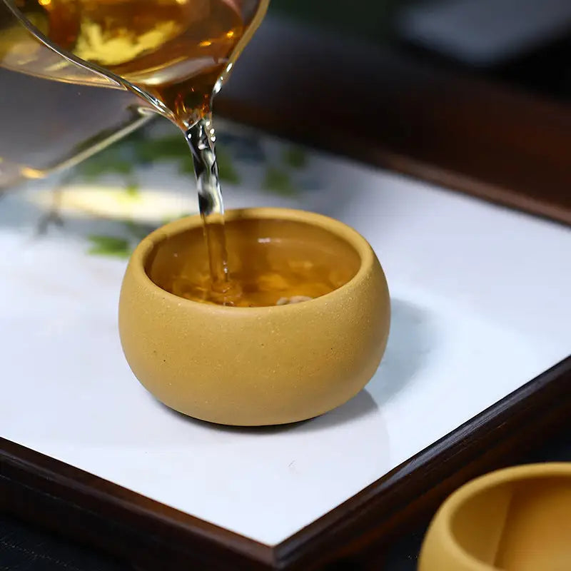 Round tan Golden Ember Cup teacup being filled, perfect for Gongfu tea set brewing