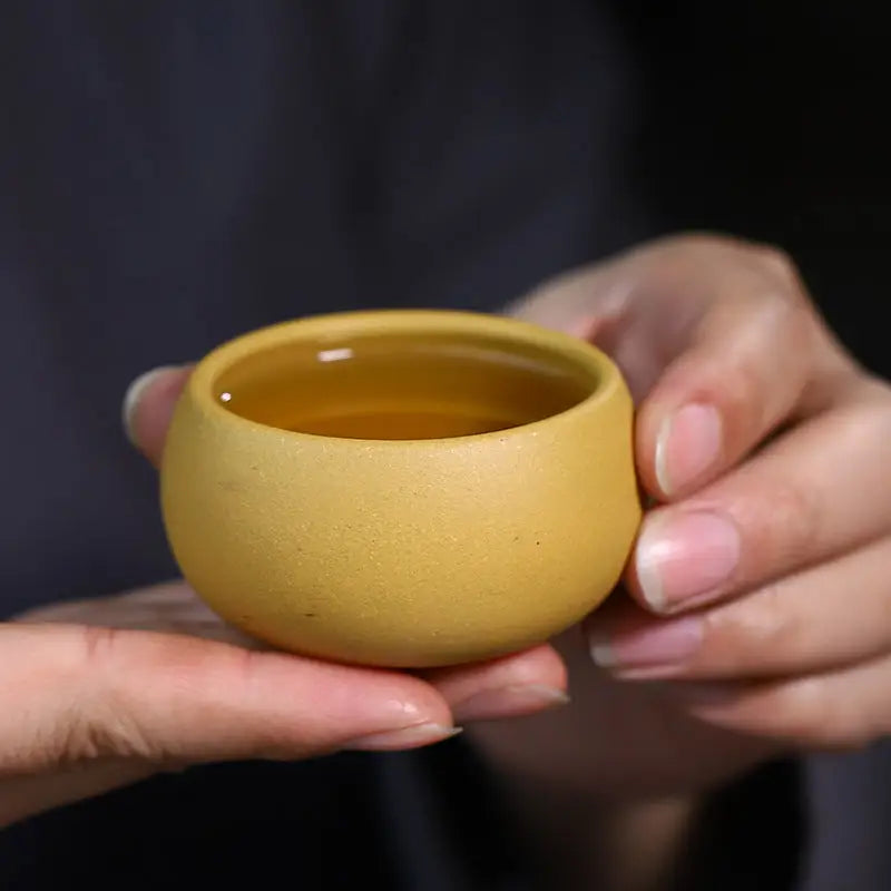 Round yellow Golden Ember Teacup with liquid, perfect for Yixing Zisha Gongfu Tea Set
