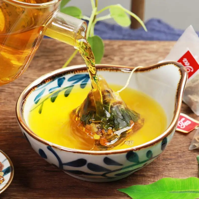 Tea being poured into a teacup with a tea bag featuring Poria Cocos for its anti-inflammatory properties in Gout Tea Health-Enhancing Herbal Tea