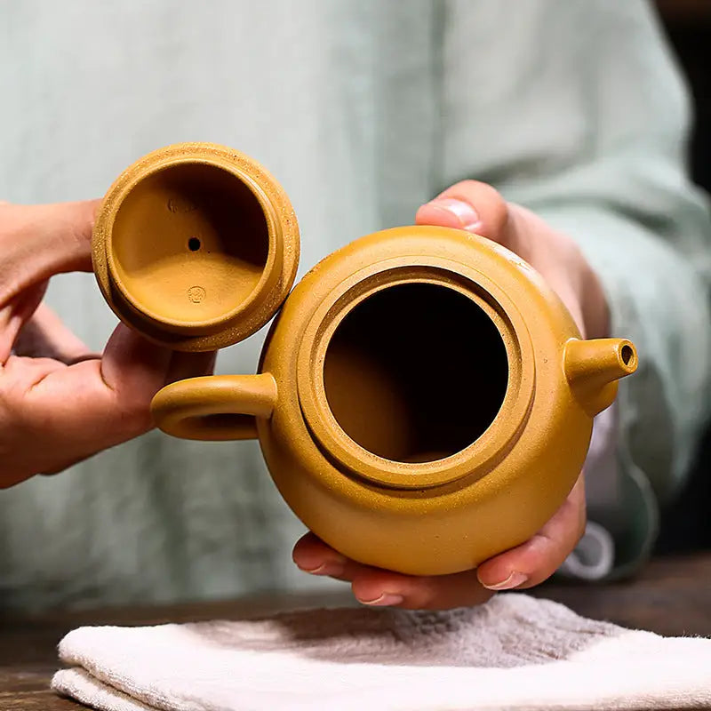 Open yellow-brown Yixing teapot with guardian beast lid in golden duanni clay style