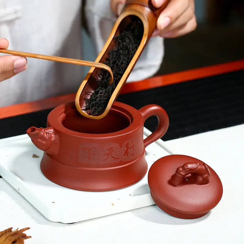 Earthenware teapot with tea leaves being added from Heaven’s Mandate, made of Yixing Zisha clay