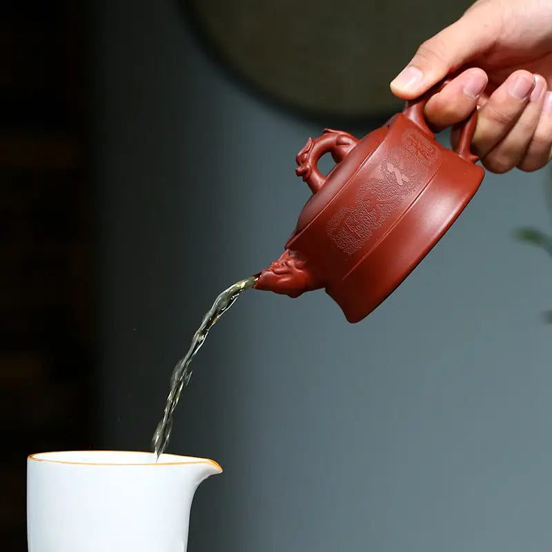 Reddish-brown Yixing Zisha clay teapot pouring liquid from Heaven’s Mandate design