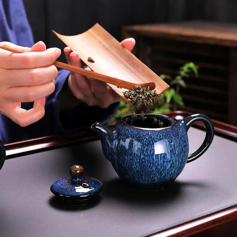 Blue ceramic teapot from Iceberg Tea Set being filled with tea, part of handcrafted Jian Zhan teaware