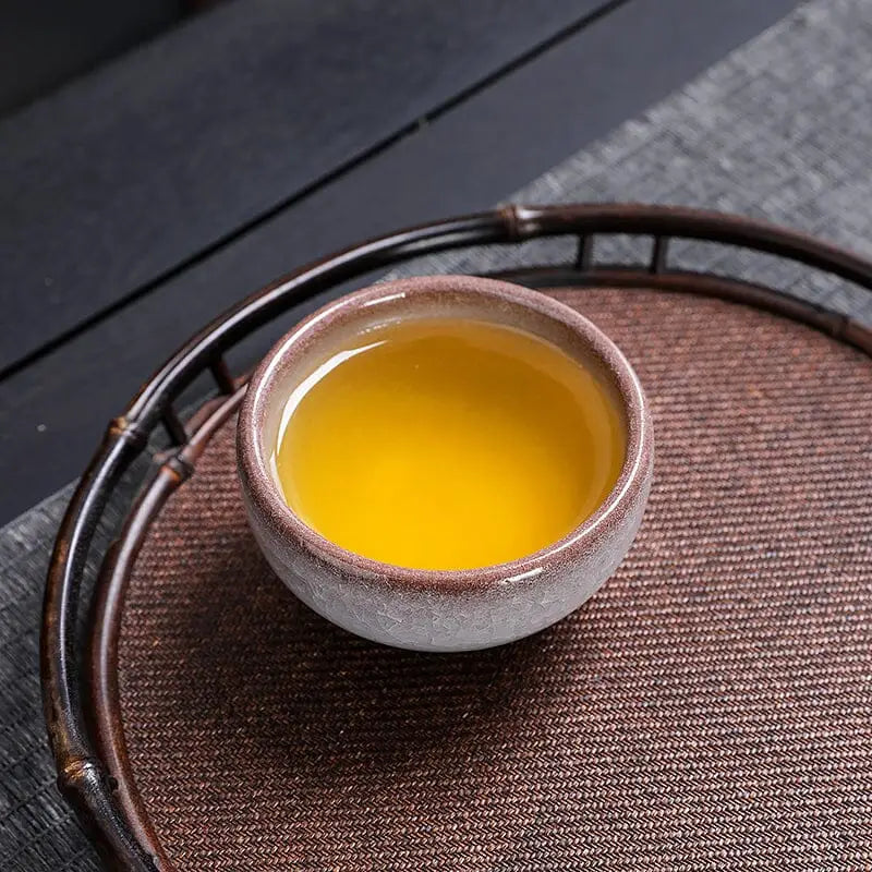 Ivory Rift crackled grape teacup with yellow liquid, showcasing Rift crackled glaze beauty