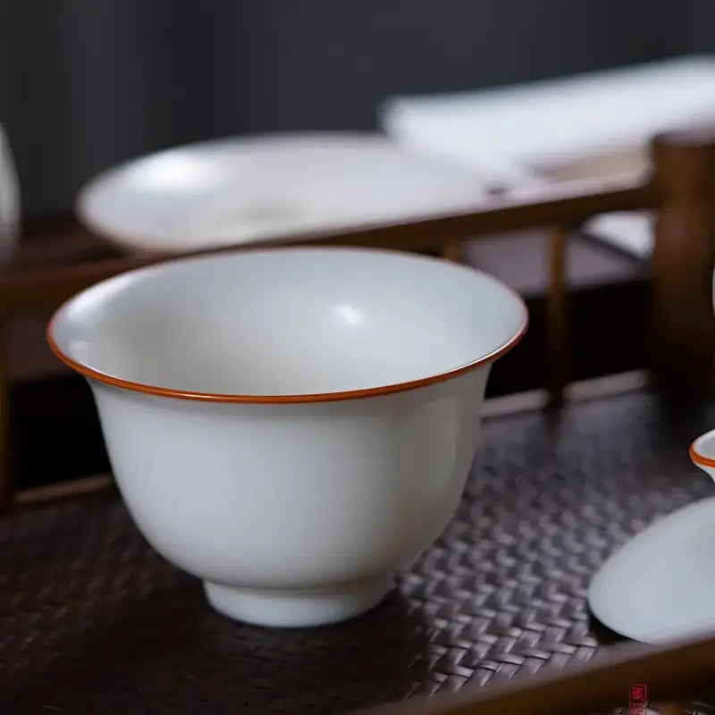 White ceramic teacup with brown rim showcasing Ivory White Ru Kiln dehua porcelain with natural agate glaze