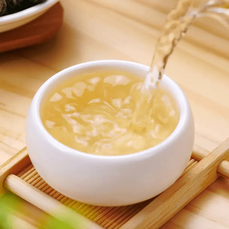 White teacup being filled with Jasmine Dragon Ball Tea Leaves, perfect for tea sets and mugs