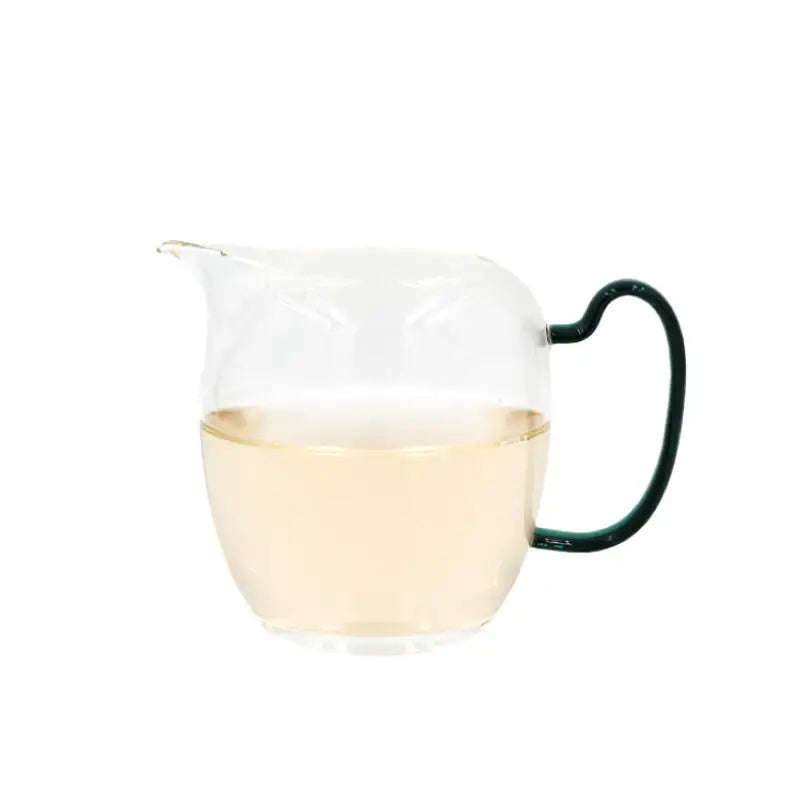 Glass pitcher with green handle and light liquid for Jasmine Silver Needle white tea infusion