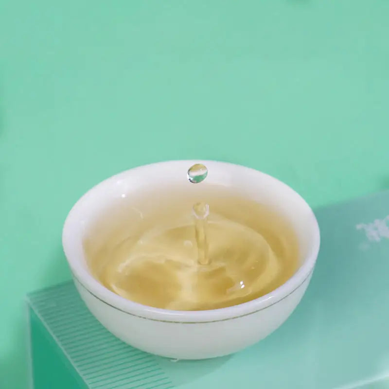 White teacup with liquid drop from Jasmine White Tea Leaves, perfect for tea sets and mugs