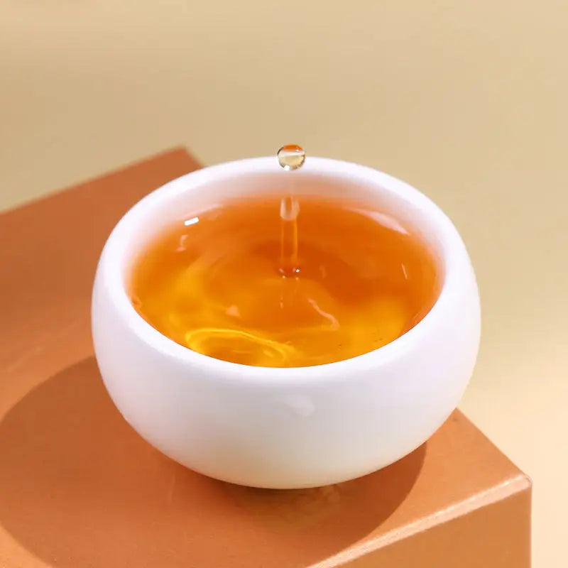 White cup with amber Jin Jun Mei Red Tea Leave liquid in a mug, perfect for tea lovers