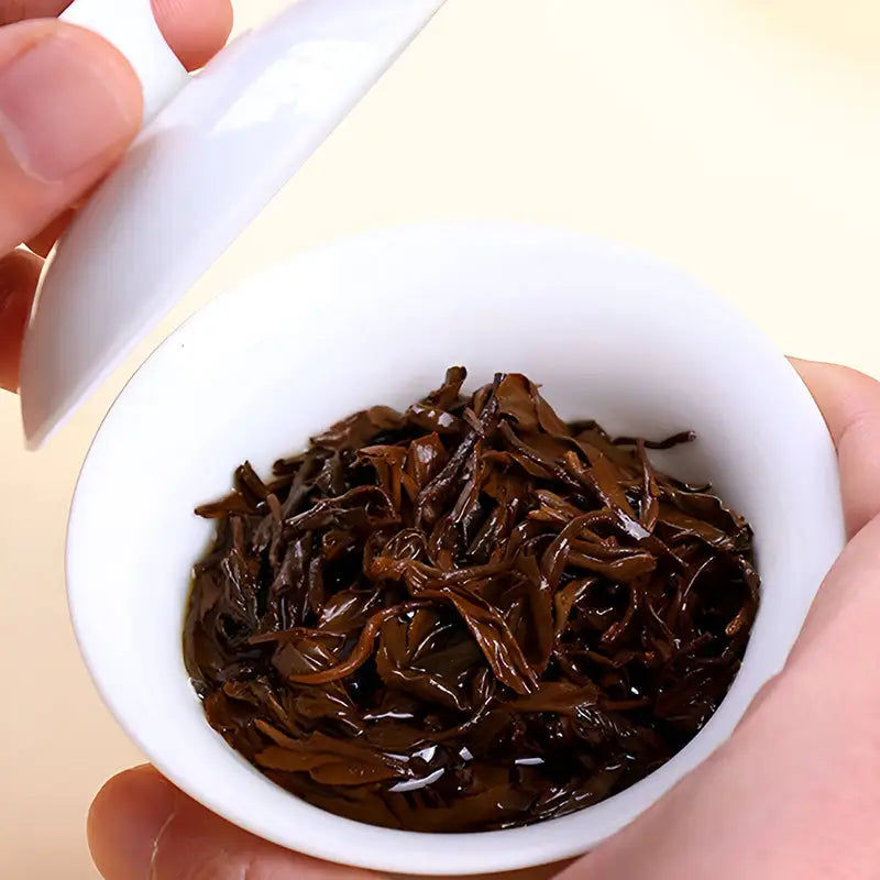 Dark steeped Jin Jun Mei Red Tea Leaves in a white Gaiwan teapot set
