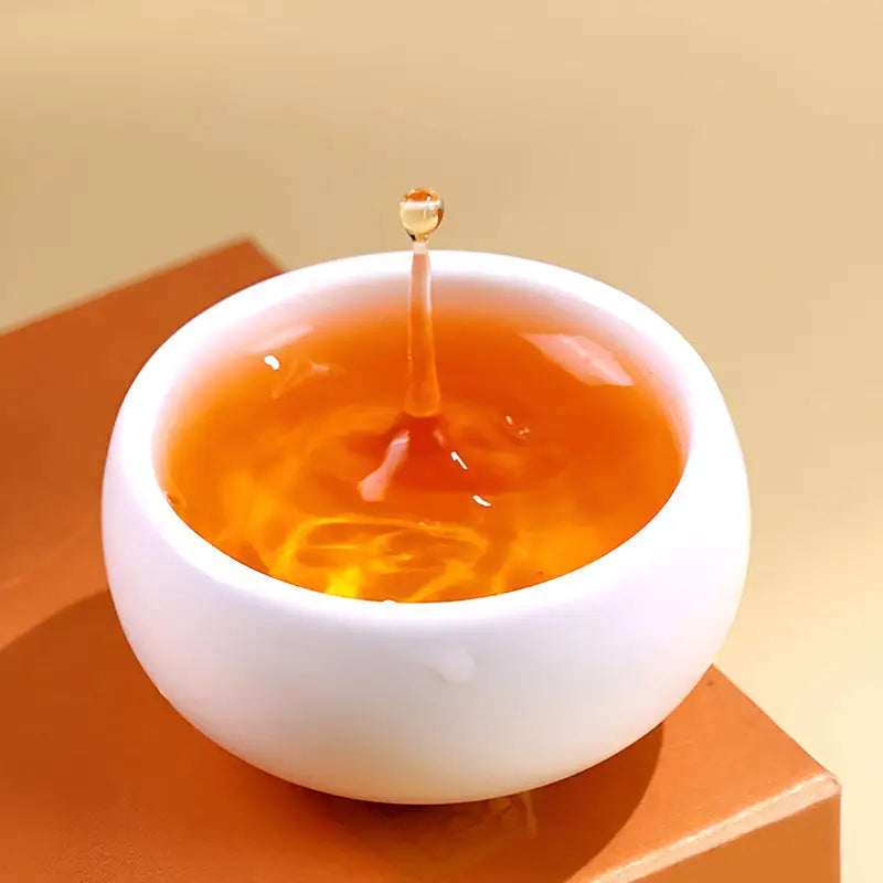 White bowl with liquid splash from Jin Jun Mei Red Tea Leaves, perfect for tea sets