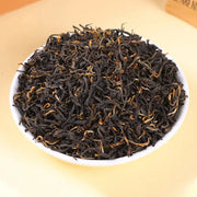 Loose black tea leaves for Jin Jun Mei Red Tea displayed with teapots and mugs