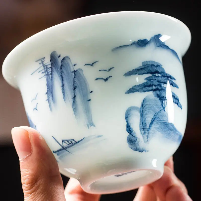 White ceramic teacup with blue mountain landscape design showcasing Jingdezhen enamel art