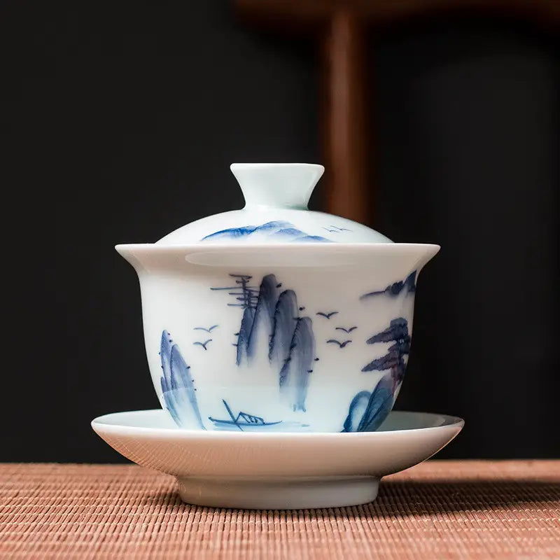 White ceramic tea cup with blue mountain landscape design showcasing Jingdezhen enamel art