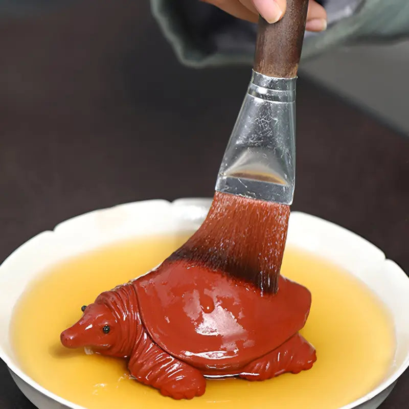 Red turtle candy being brushed as Longevity Turtle tea pet made from Yixing Zisha clay, water element tea pet