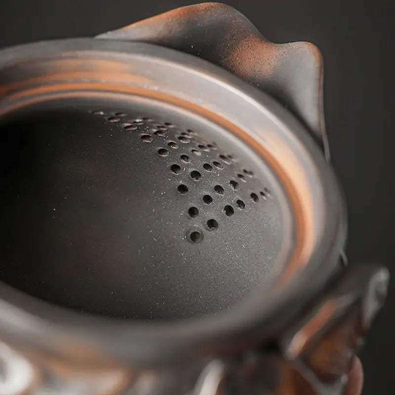 Dark ceramic Lotus Pod teapot interior with strainer holes in Jianshui Zitao style