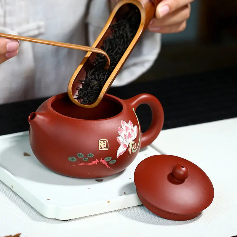 Red-brown yixing zisha teapot with hand-painted lotus flower design in purple clay