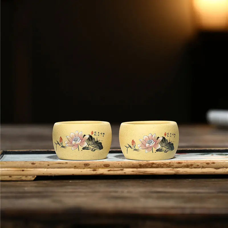 Two yellow hand-painted Yixing Zisha teacups with lotus flower designs for Lotus Serenity