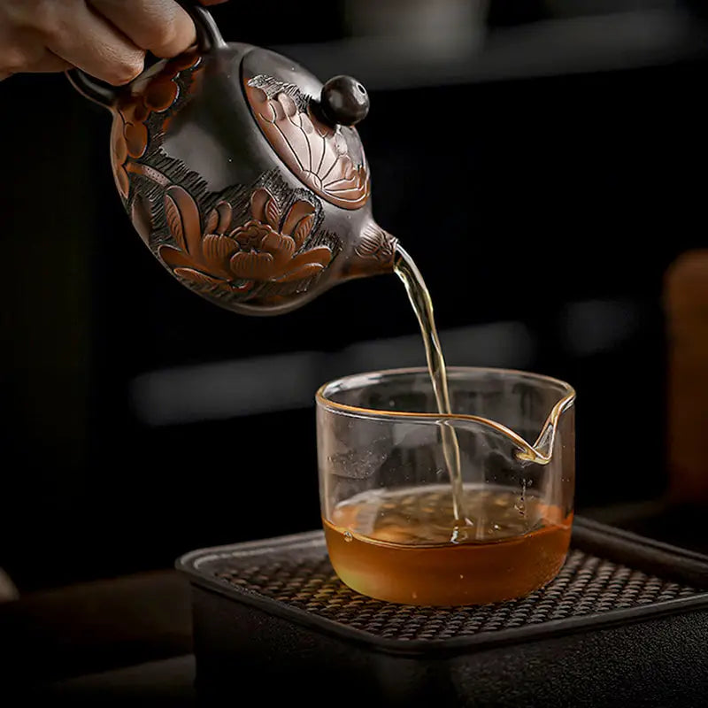 Ornate Lotus teapot pouring tea, handcrafted from zisha clay with a hand-carved lotus design
