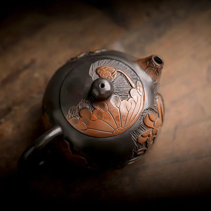 Ornate dark Lotus teapot with copper accents, crafted from hand-carved Zisha clay