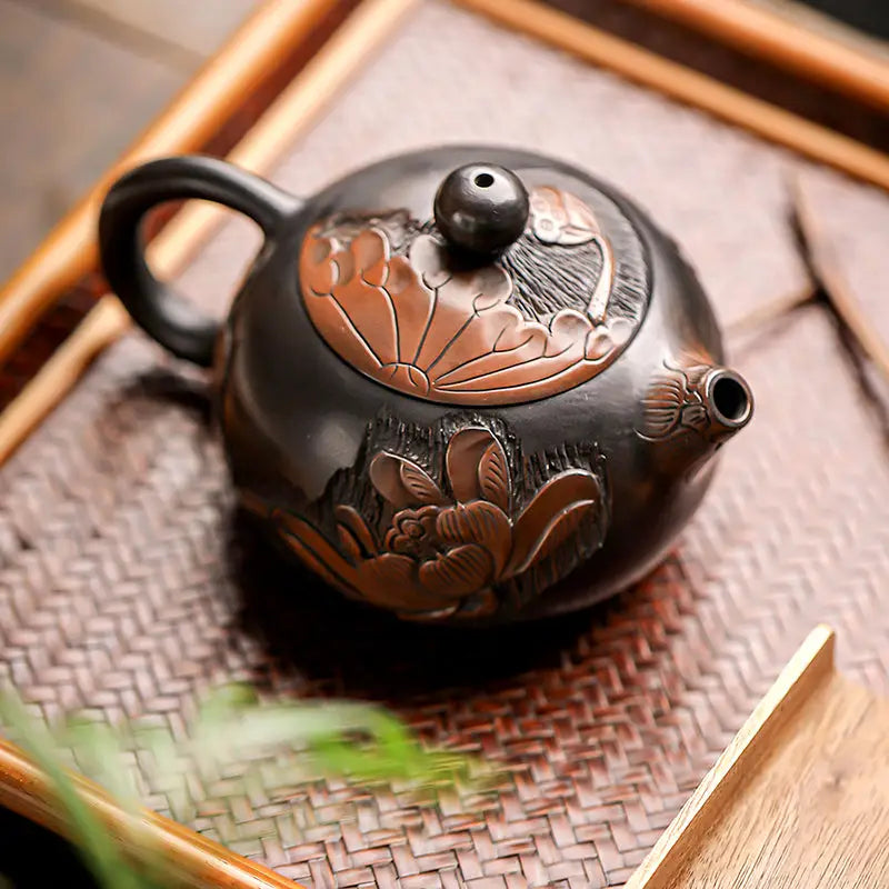 Dark round Zisha clay lotus teapot with intricate hand-carved floral carvings