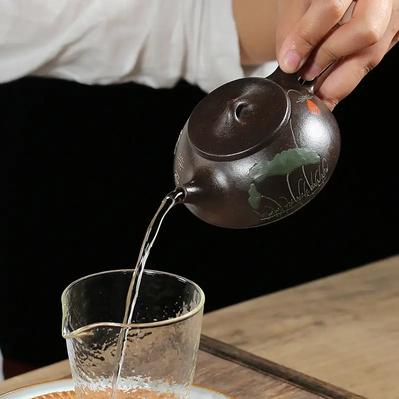Brown Yixing Zisha teapot pouring liquid into glass from Lotus Whisper hand-carved Lotus
