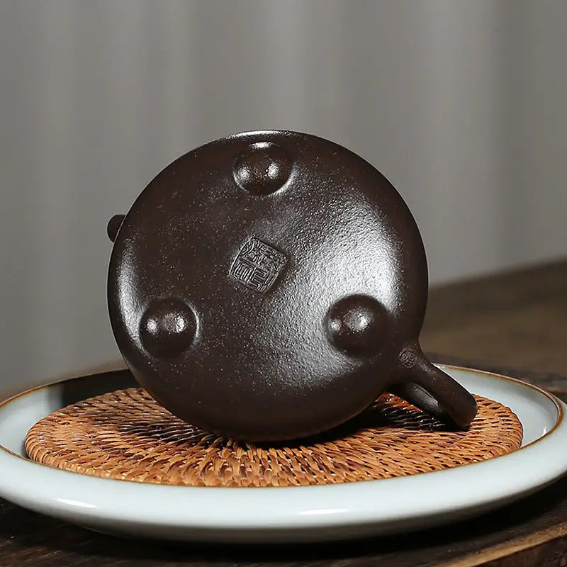Round brown Yixing Zisha teapot base with three legs and hand-carved lotus design