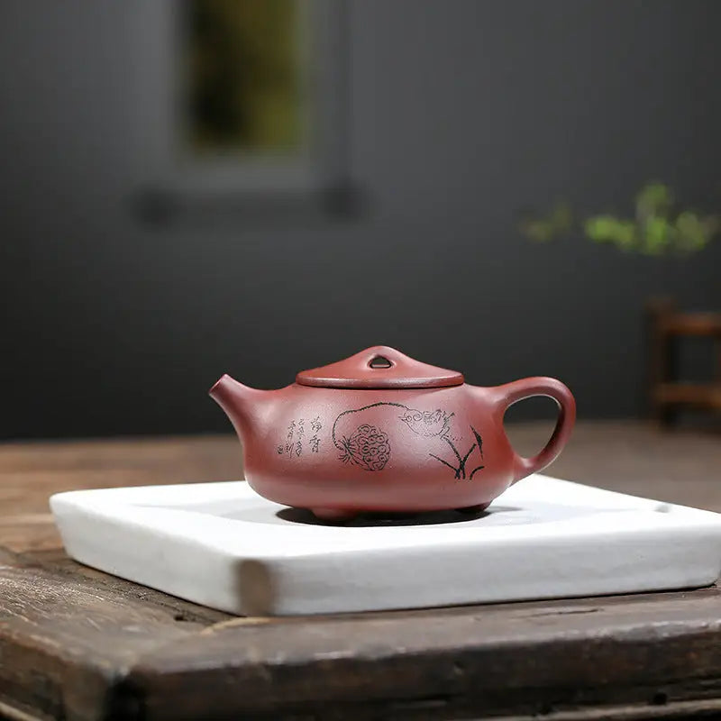 Maroon ceramic Lotus Whisper Yixing teapot with floral design and lotus pods detail