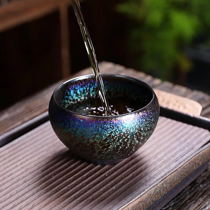Iridescent glaze tea cup from Magic Jian Zhan being filled with tea for gongfu tea ritual