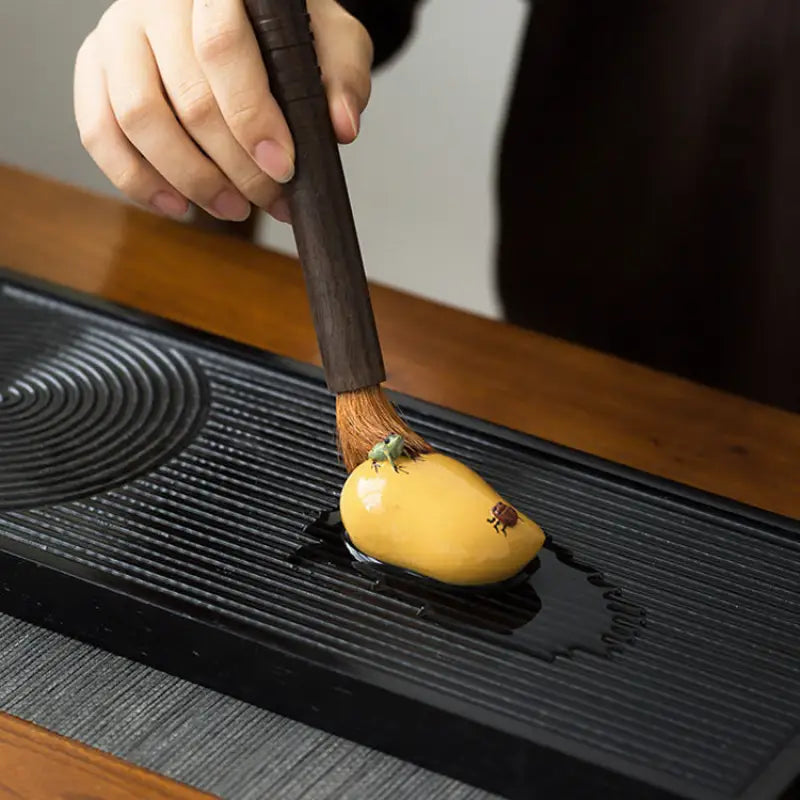 Yellow mango-shaped tea pet being brushed, perfect for charming tea and feng shui decor