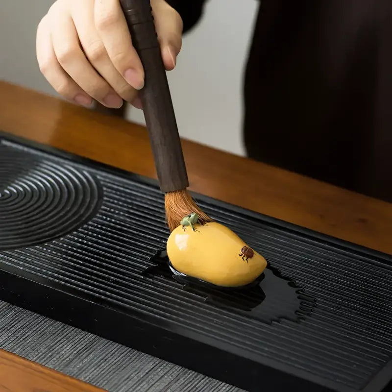 Yellow mango-shaped tea pet being brushed, perfect for charming tea and feng shui decor