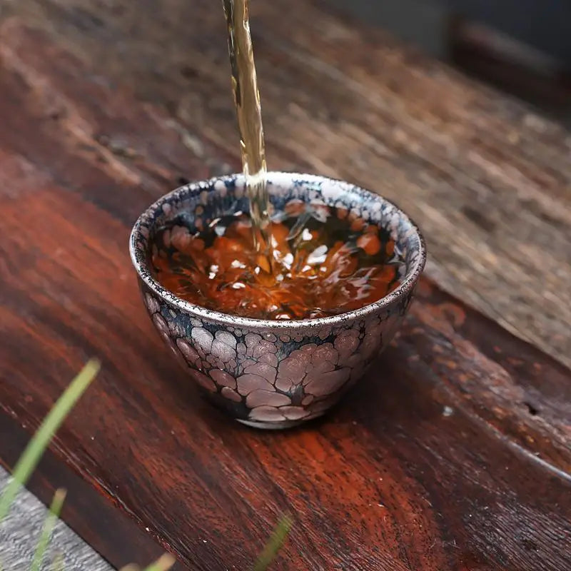 Tea being poured into a decorative Molten Jian Zhan tenmoku ceramics cup for gongfu tea