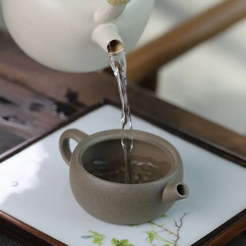 Pouring tea into the Moonbridge harmony teapot with raised handle Yixing Zisha craftsmanship