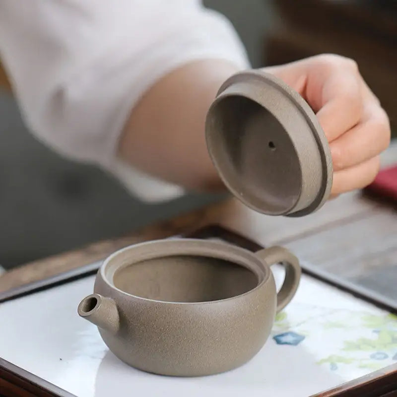 Unglazed clay teapot with lid from Moonbridge Harmony Teapot collection featuring raised handle Yixing Zisha style