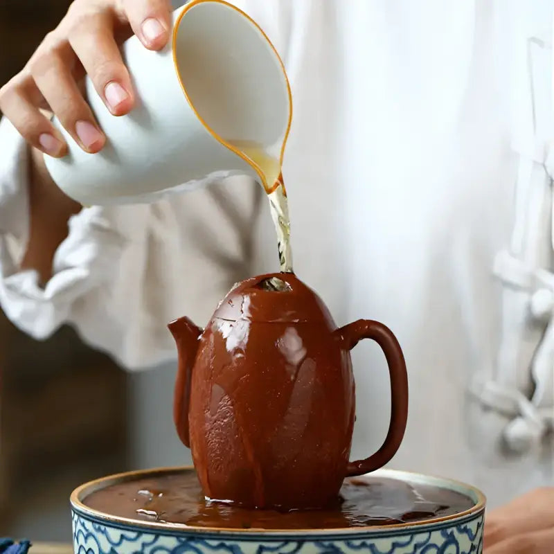 Brown Yixing Zisha Mountain River teapot being filled, 220ml Mountain River style