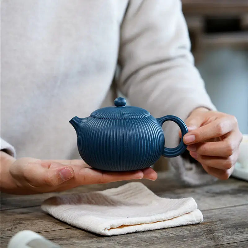 Blue ribbed ceramic teapot with vertical ridges, resembling a yixing zisha teapot in midnight ripple style