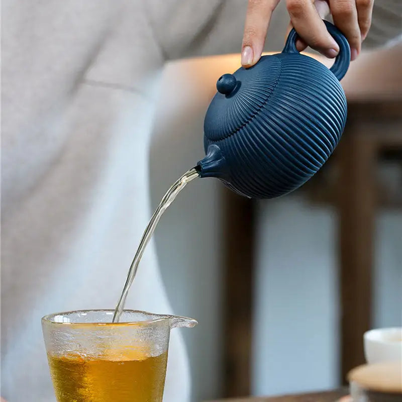 Blue Yixing Zisha teapot with midnight ripple design pouring tea showcasing vertical ridges