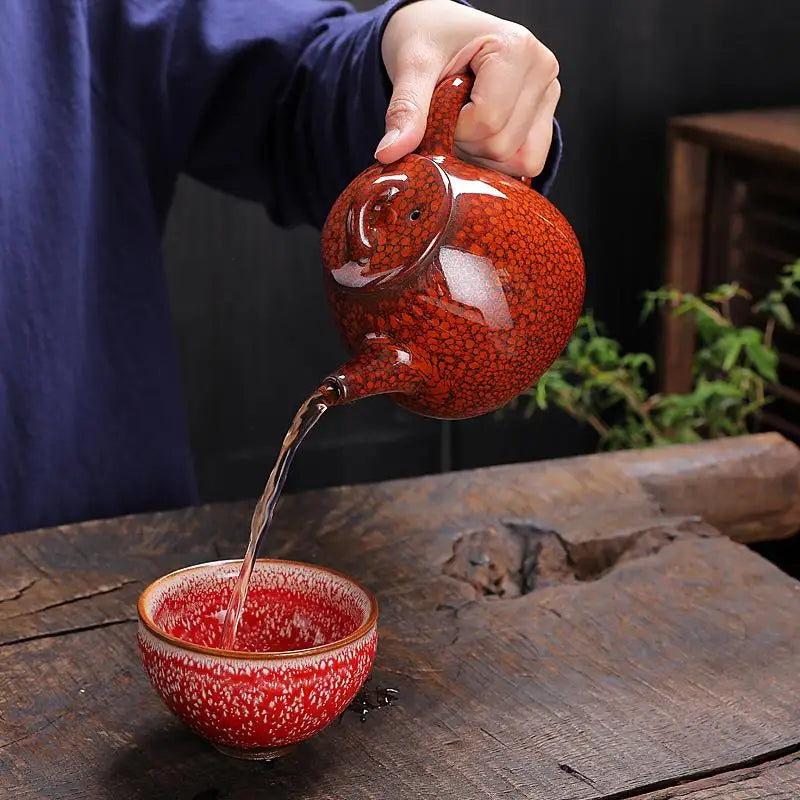 Red speckled Teapot pouring liquid showcasing jianshui red clay and glazed texture for gongfu tea