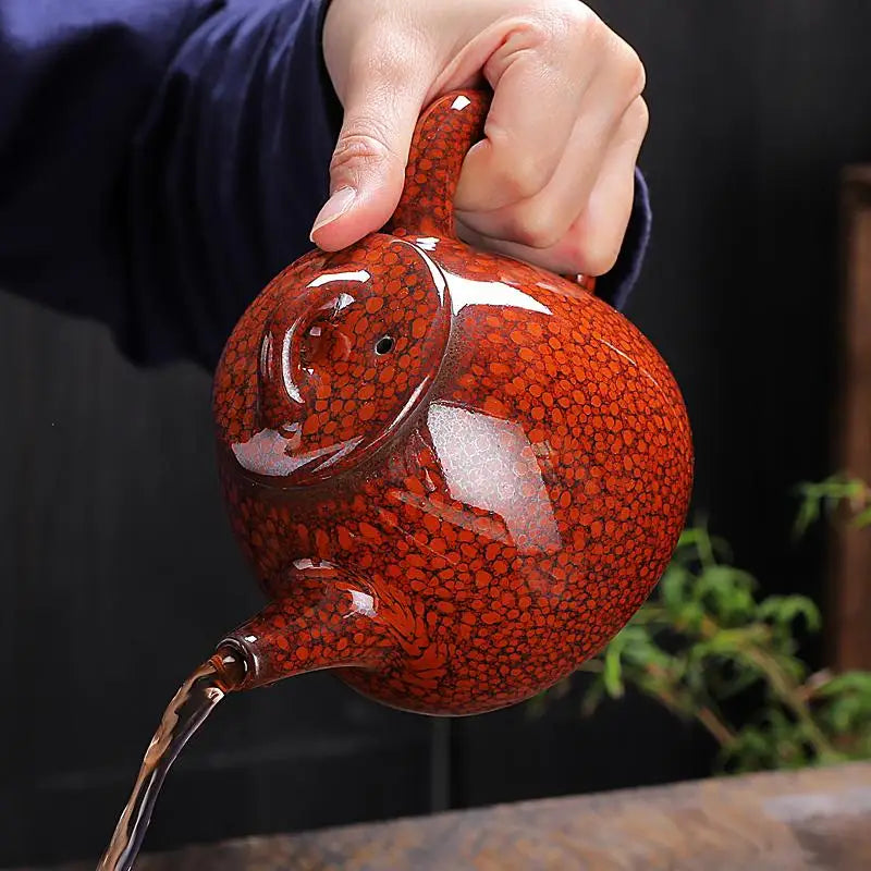 Red-speckled ceramic teapot pouring liquid highlighting jianshui red clay and glazed texture