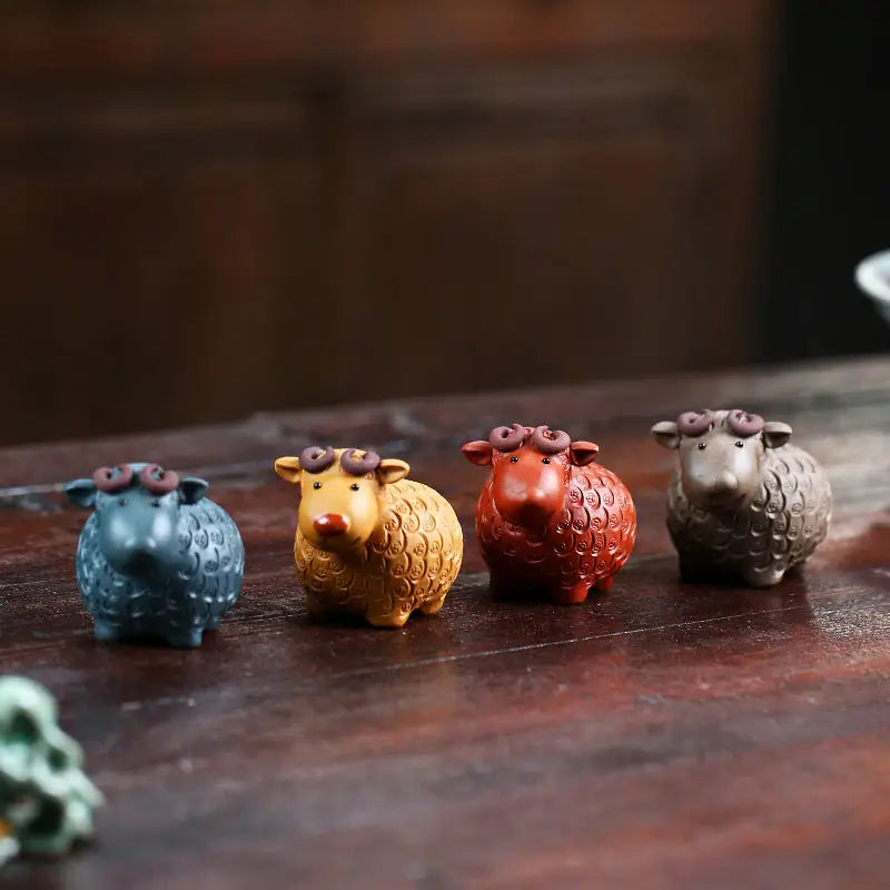 Four colorful sheep figurines from Peaceful Ram tea pets guide made of Zisha clay for feng shui