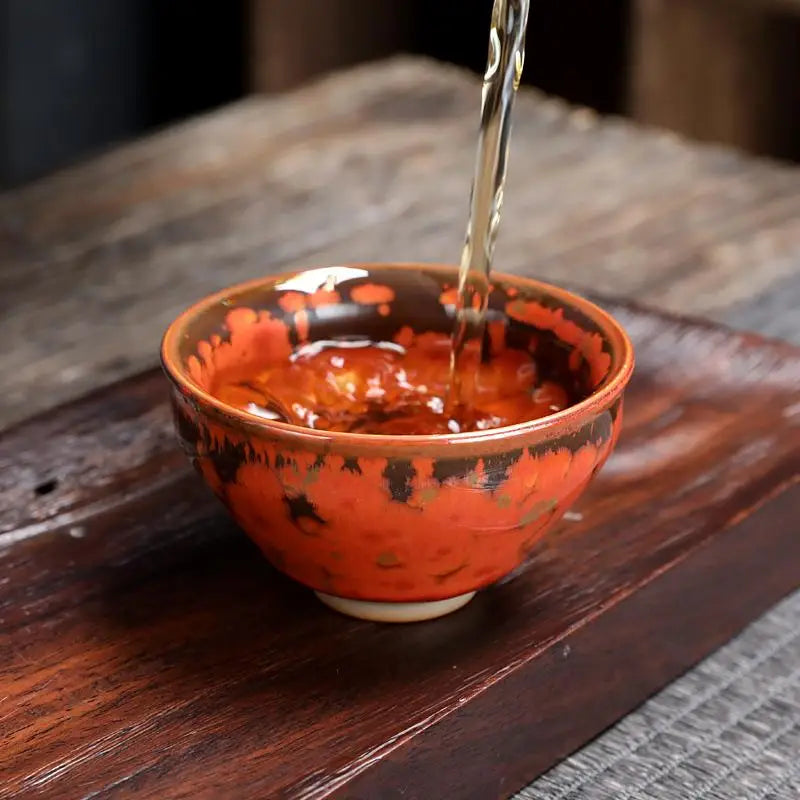 Orange and brown ceramic teacup with volcanic glaze showcasing Phoenix Jian Zhan style