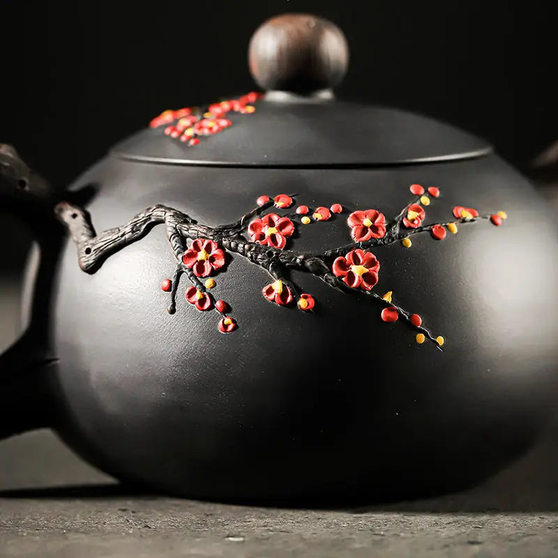 Black Yixing Zisha Plum Blossom teapot with floral branch design for elegant tea brewing