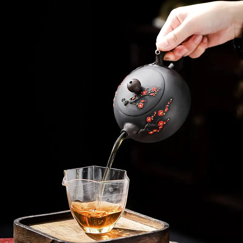Black Yixing Zisha teapot pouring tea from Plum Blossom teapots, elegant and authentic