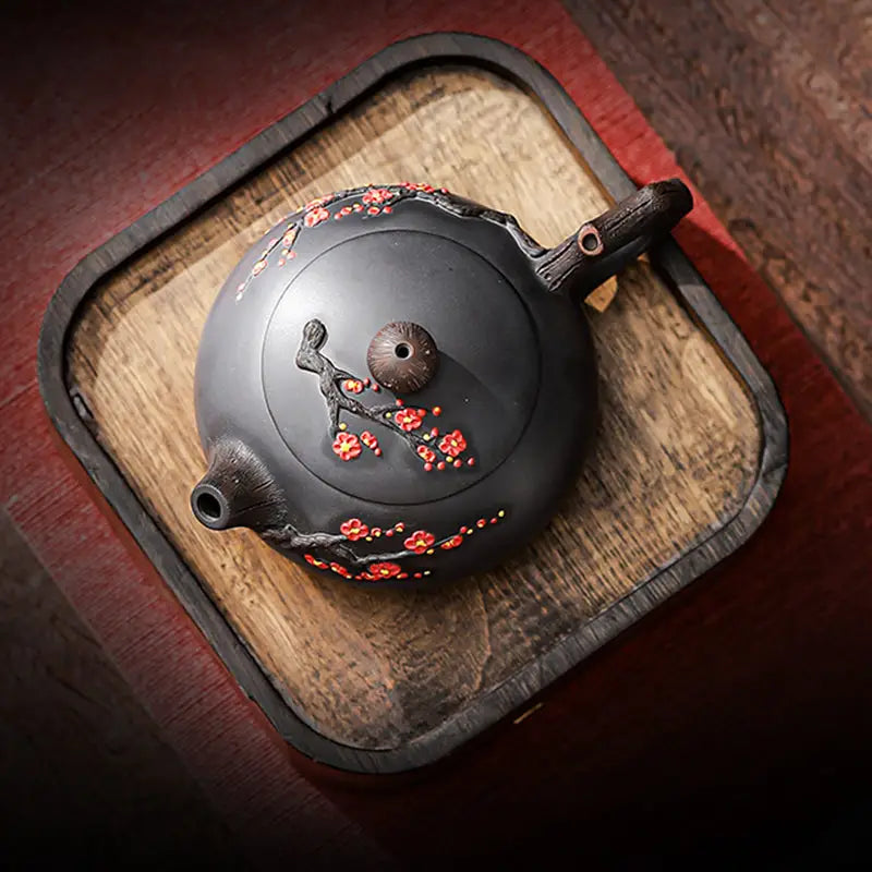 Dark Yixing Zisha teapot with floral accents named Plum Blossom for elegant tea brewing