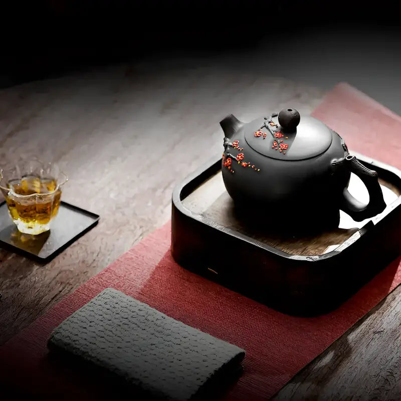 Black Yixing Zisha teapot with red floral accents from the Plum Blossom collection