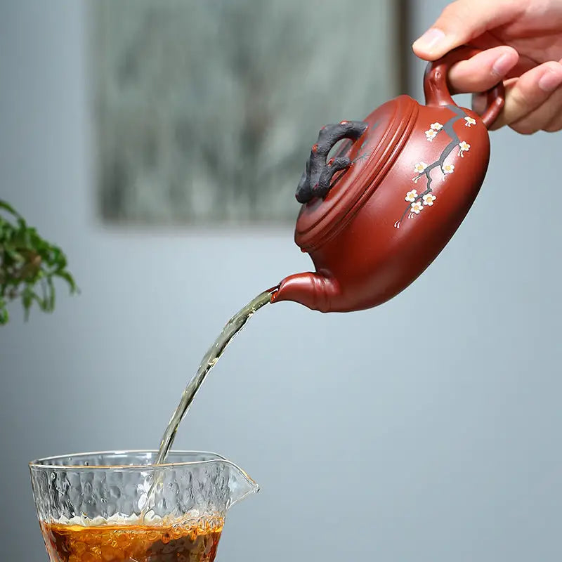 Red clay teapot pouring tea with Plum Blossom motif, perfect for handcrafted Yixing Zisha Gongfu Tea